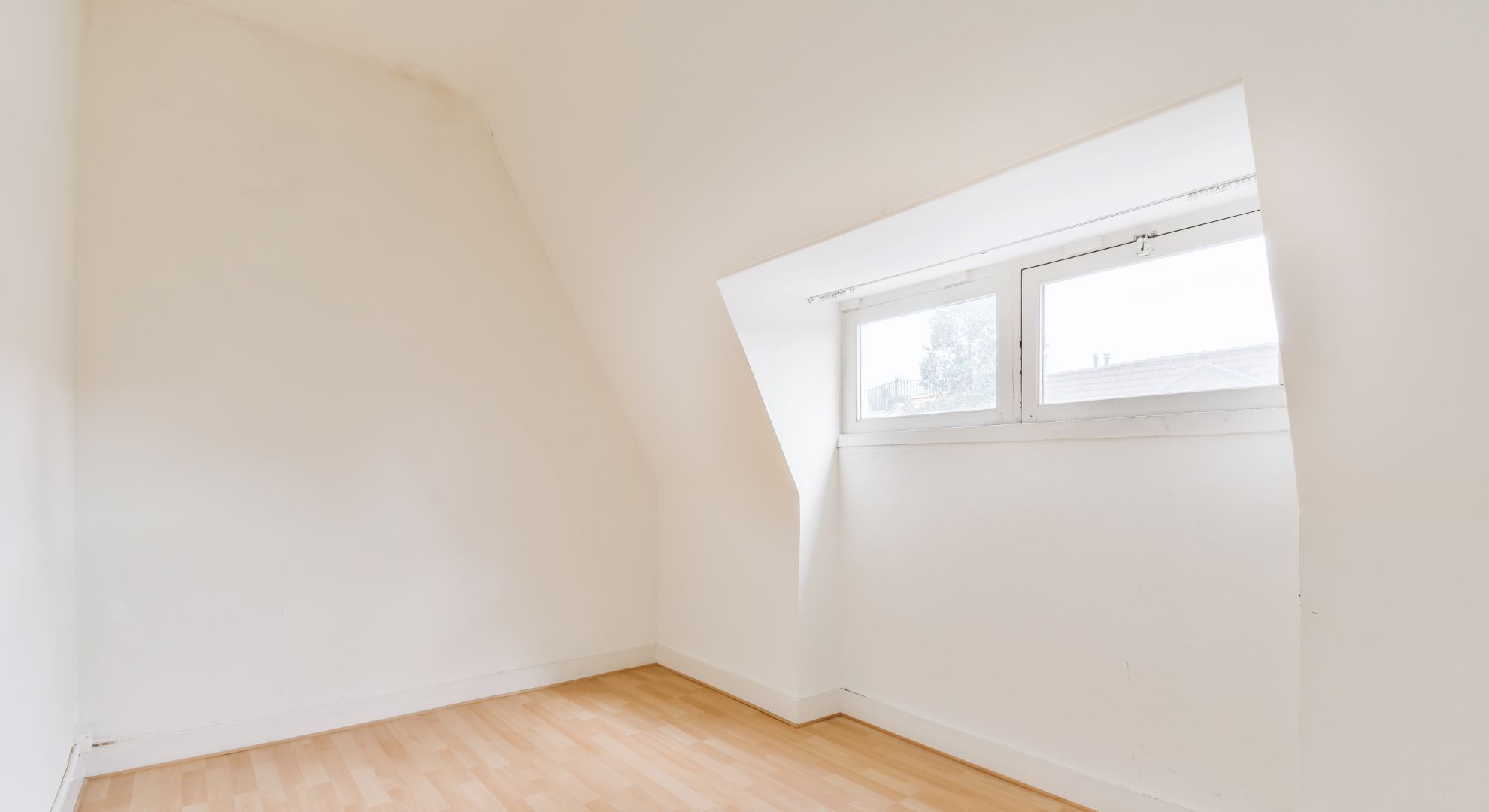 Habitación abuhardillada con paredes alisadas y pintadas en blanco