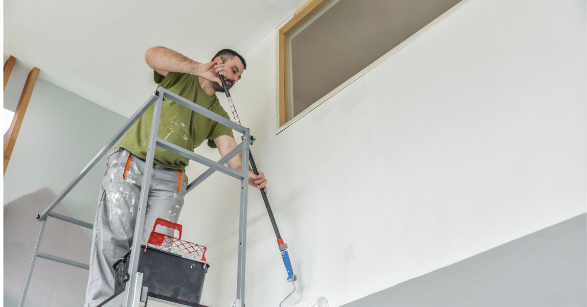 Pintor pintando con rodillo y alargador